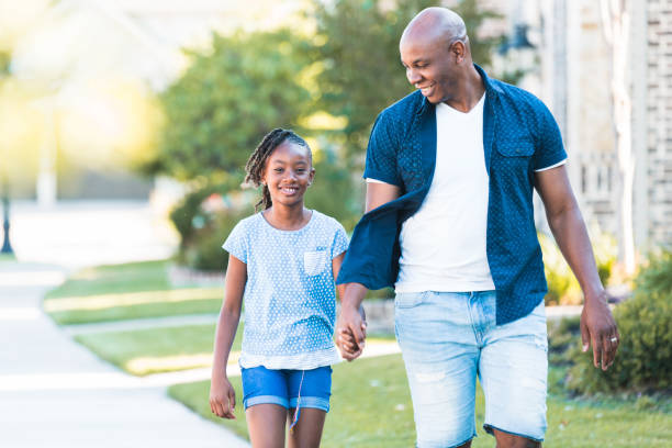 istock Dad holds preteen daughter's hand while walking 1254705306