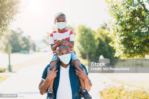 Dad Gives Son Piggy Back Ride Both Wear Masks Stock Photo - Download Image Now - Protective Face Mask, Family, COVID-19