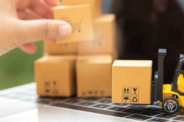 istock Mini forklift truck load cardboard box and hand holding carton put on stack of boxes behind on laptop keyboard. Logistics and transportation management ideas and Industry business commercial concept. 1254706016