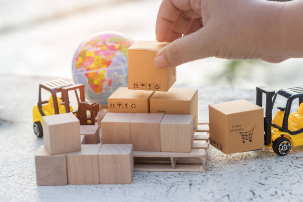 istock Handle box on stack of cardboard boxes with symbol by hand. Mini forklift truck load  box and globe near by. Logistics and transportation management ideas and Industry business commercial concept. 1254706031