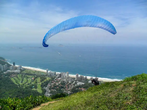 Photo of man paragliding on the flight path of the beautiful rock in Rio de Janeiro