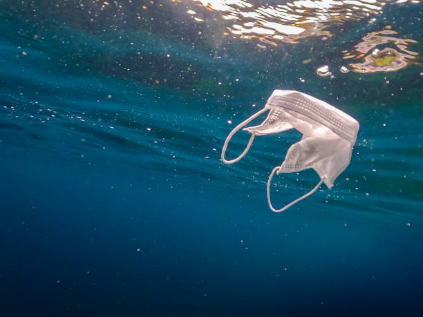 istock Protective mask discarded and thrown on the ocean. Abandoned facemask 1254710476