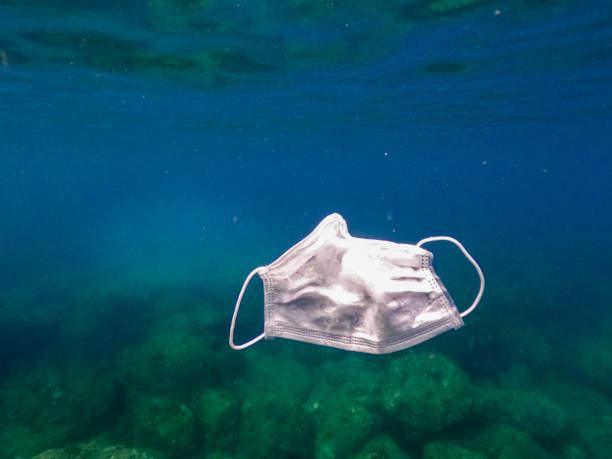 istock Protective mask discarded and thrown on the ocean. Abandoned facemask 1254710490