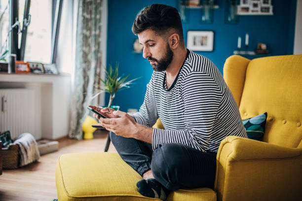 istock Man sitting in chair at home and using smart phone 1254714123