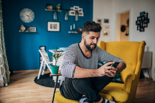 istock Man sitting in chair at home and using smart phone 1254714133