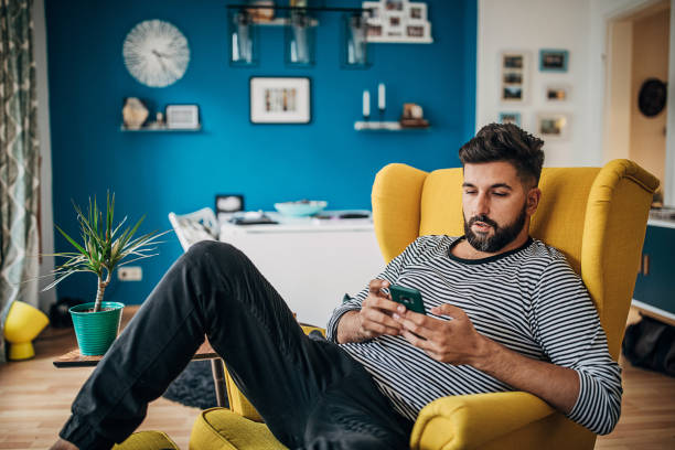 istock Man sitting in chair at home and using smart phone 1254714148