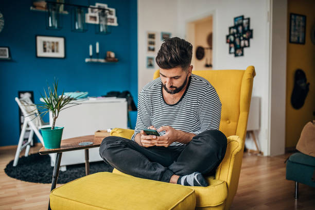 istock Man sitting in chair at home and using smart phone 1254714162
