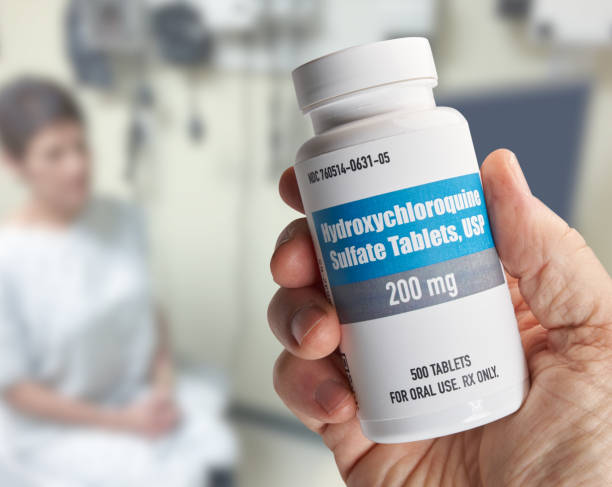 istock Hydroxychloroquine bottle held in hand in doctors office with patient 1254719448