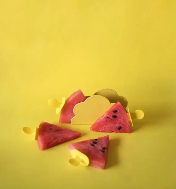 Photo of Watermelon slices on an ice cream stick on an yelloow background. Creative idea