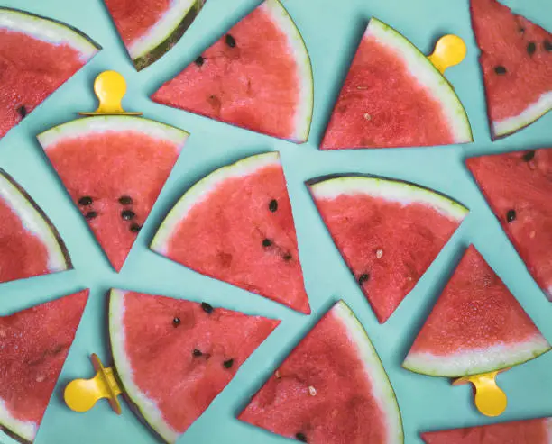 Photo of Pattern of watermelon slices on an ice cream stick on a blue background. Creative idea