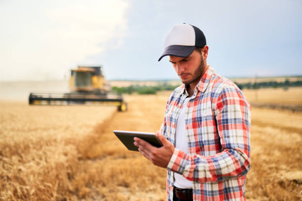 istock Precision farming. Farmer holding tablet for combine harvester guidance and control with modern automation system. Agronomist using online data management software generating yield maps at wheat field 1254723397