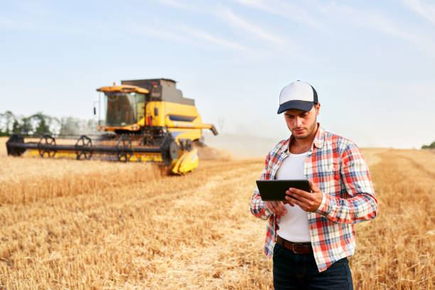istock Precision farming. Farmer holding tablet for combine harvester guidance and control with modern automation system. Agronomist using online data management software generating yield maps at wheat field 1254723439