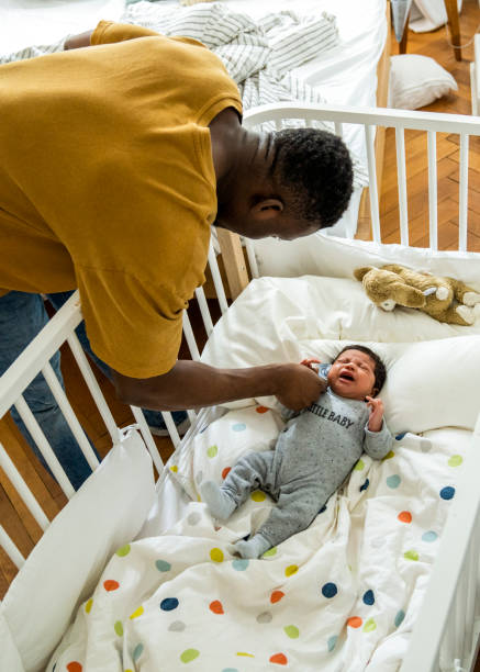 istock Father playing with crying baby boy lying in crib 1254725533