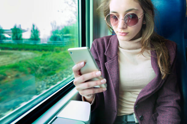 istock Young girl using smart phone in subway train 1254728052