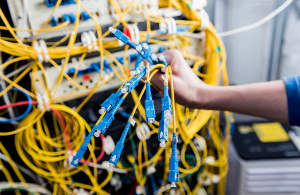 istock Network engineer working in server room. Connecting network cables to switches 1254730520