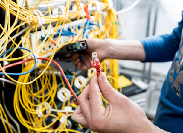 istock Network engineer working in server room. Connecting network cables to switches 1254731137