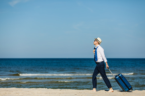 Businessman standing with suitcase at seaside