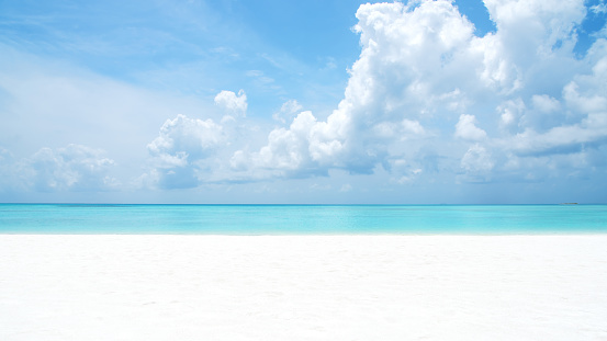 White sand beach and turquoise tropical sea with clouds sky