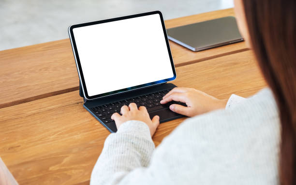istock a woman using and typing on tablet keyboard with blank white desktop screen as a computer pc on the table 1254741569
