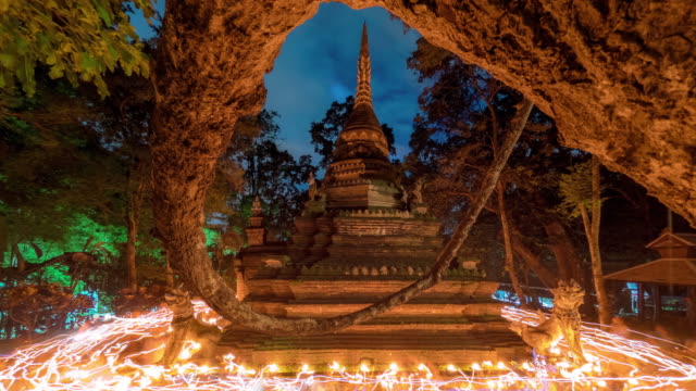 Time Lapse Candle procession ceremony around ancient pagoda in twilight on Buddhist Lent Day