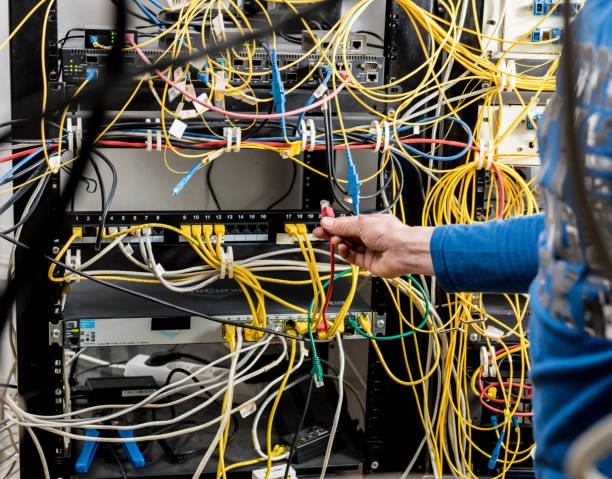 istock Network engineer working in server room. Connecting network cables to switches 1254744951