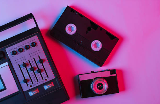 istock Retro audio tape recorder, camera, video cassette in pink bue gradient neon light. Retro media. 80s. Top view. 1254745866