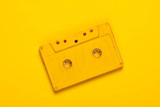 istock Yellow audio cassette on yellow background. 80s. Top view 1254746181