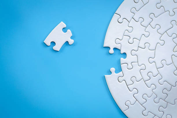 istock White jigsaw pieces on a blue background, Copy space, Concept image of unfinished task.  missing jigsaw puzzle pieces and business concept with a puzzle piece missing. 1254746231