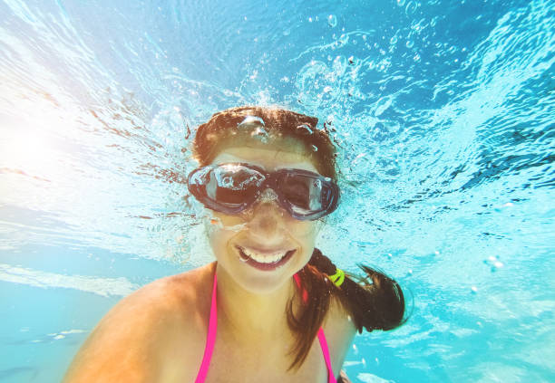 istock Smiling girl swimming underwater in pool 1254747450