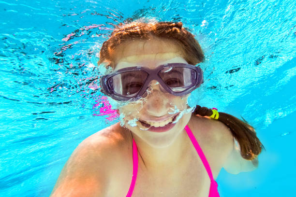 istock Smiling girl swimming underwater in pool 1254747454