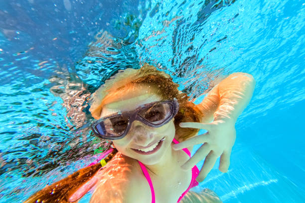istock Smiling girl swimming underwater in pool 1254747455
