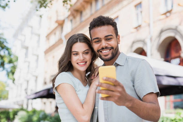 istock Beautiful happy couple using smartphone in a city 1254747980
