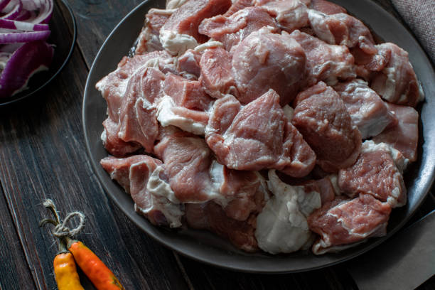 istock Raw mutton cut into medium pieces, lay on a plate, surrounded by red onions, a knife and chili peppers, tied with twine 1254750343
