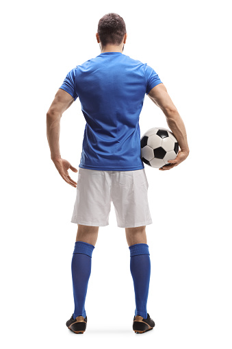 Full length rear shot of a soccer player with a ball under arm isolated on white background