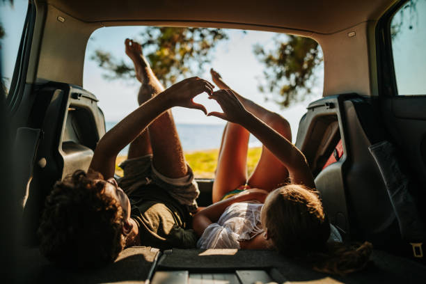 casal jovem amoroso desfrutando vista do mar do porta-malas de carro aberto - car rear view behind car trunk - fotografias e filmes do acervo