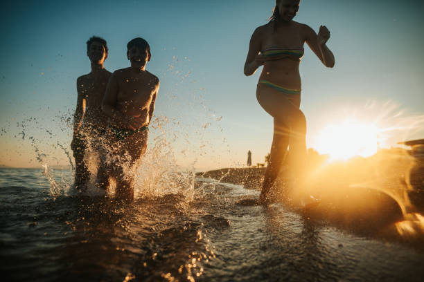 istock Brothers and sister playing in sea on sunset 1254753601