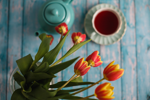 High angle view of rustic table with colorful tulip flowers and rooibos tea.