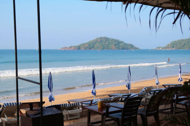 istock Image of restaurant tables and chairs ready for alfresco dining with beach view, overlooking parasols and loungers on Palolem Beach and Arabian Sea, Goa, South India 1254754273