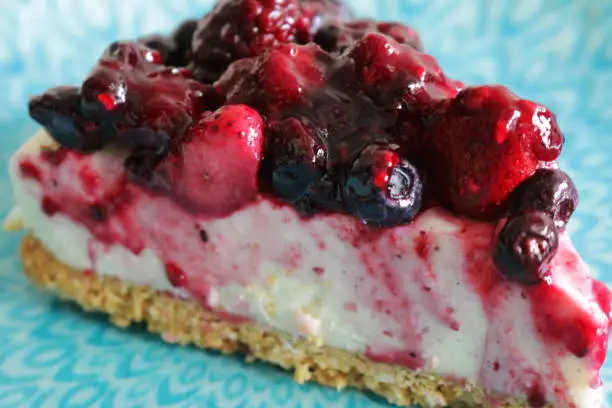 Stock photo showing summer fruits cheesecake with buttery biscuit base, vanilla mascarpone cream cheese for dessert pudding after restaurant dinner.