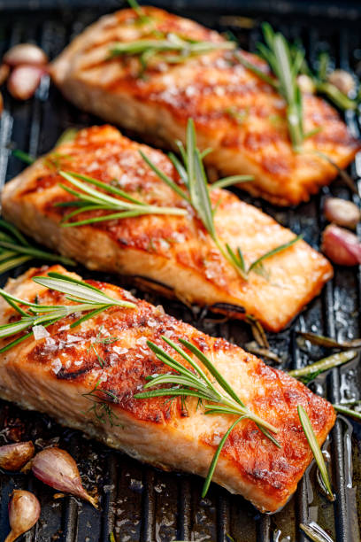 filetes de salmón a la parrilla espolvoreados con romero fresco y jugo de limón - baked salmon fotografías e imágenes de stock