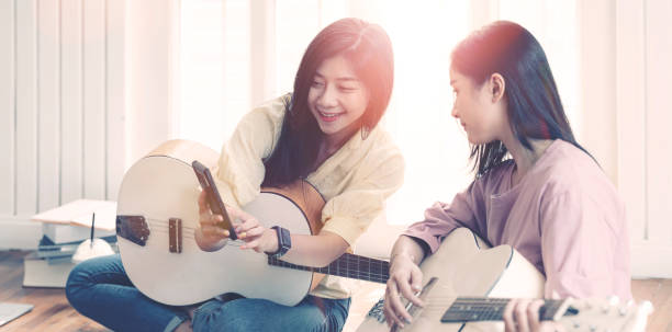 istock Two young women singing and playing guitar together. 1254759818
