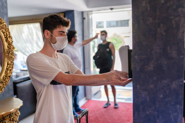 Millennial traveler disinfection his hands on hotel reception