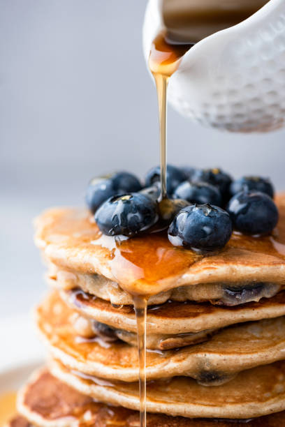 jarabe de arce vertiendo en una pila de panqueques - pancake buttermilk buttermilk pancakes equipment fotografías e imágenes de stock