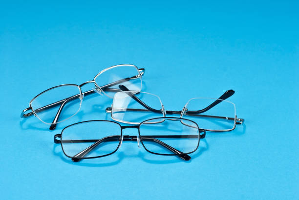 istock Different types of glasses on a blue background close up. Glasses with rectangular and round frames. Layout for design. Space for text and free space near the object. 1254763826