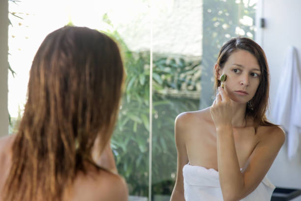 istock Face massage. Woman using jade face roller for skin care. 1254764199