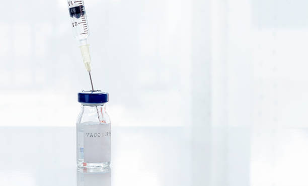 istock Vaccine bottles with a plastic disposable syringe on a white top table. 1254764393
