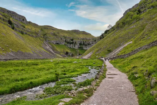 June 2019, Malham, Yorkshire Dales, England, UK. A group of walkers hiking in the Yorkshire Dales into the gorge known as Gordale Scar.