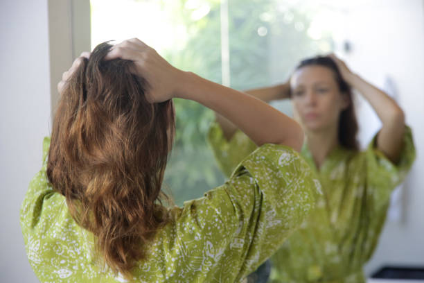 Young brunette applying hair oil with her fingers in the bathroom Young brunette applying hair oil with her fingers in the bathroom frizzy stock pictures, royalty-free photos & images