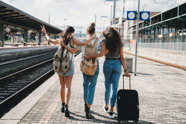 Three friends enjoying a trip together - Rear view Three friends enjoying a trip together - Rear view. They are at a railroad train station. passenger train stock pictures, royalty-free photos & images