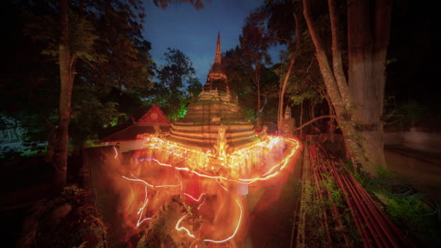 Time Lapse Candle procession ceremony around ancient pagoda in twilight on Buddhist Lent Day